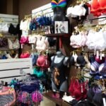 A retail store with various bras in different colors and styles displayed on a wall and racks. A mannequin is also present.